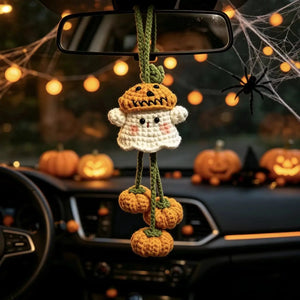 Crochet pumpkin ghost charm hanging from a car rear-view mirror with Halloween decor
